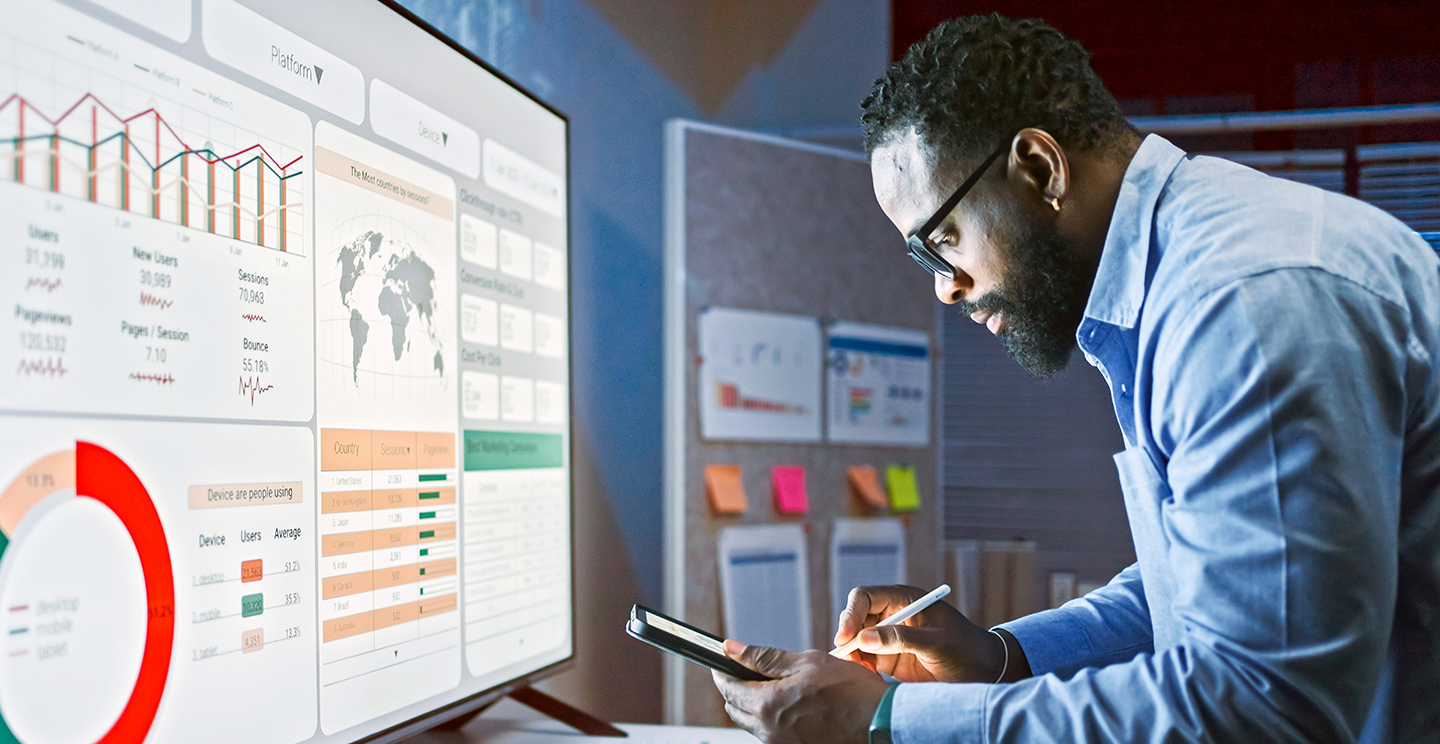 Man looking at a device and an online dashboard.