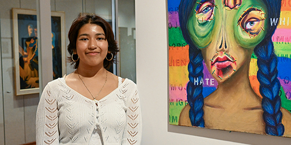 Jocelyn Olivera ’28 stands next to her artwork, "Alien"