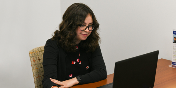 Student working on her resume in front of a laptop.